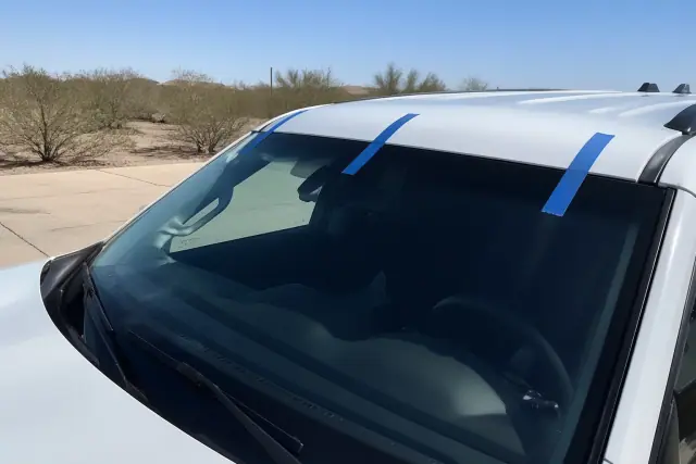 Newly installed windshield with retention tape on a vehicle in an Avondale, AZ driveway.