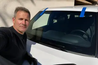 Technician inspecting a newly installed windshield with blue retention tape on a car in Phoenix, AZ.