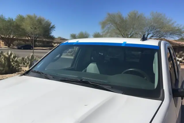 A newly installed car windshield with retention tape held in place at a worksite in Glendale, AZ.