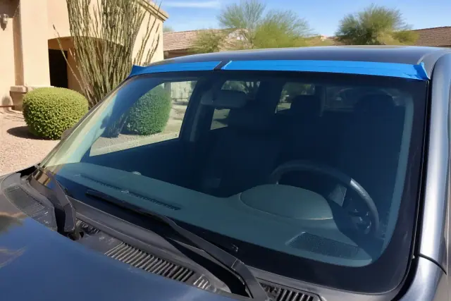 Newly installed windshield held by retention tape on a vehicle in a residential driveway in Gilbert, AZ.