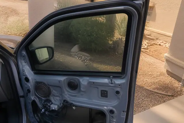 Completed door glass replacement on a vehicle at a job site in Phoenix, AZ, with stucco walls and desert landscaping.