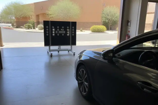 Technician performing dynamic road-test ADAS calibration in front of a vehicle at a service bay in Phoenix, AZ.