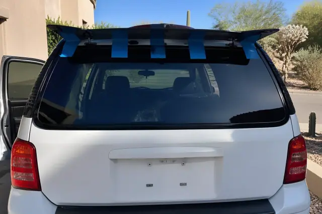 Newly installed feature-integrated rear glass with retention tape on a vehicle in Phoenix, AZ.