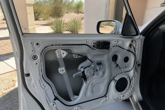Technician repairing a car window regulator inside a door panel in Phoenix, AZ.