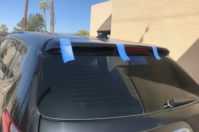 Newly installed rear vehicle glass with professional retention tape held in place in the Phoenix, AZ sun.