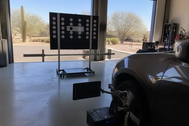 Technician performing lidar calibration on a vehicle in a Phoenix, AZ service bay with desert scenery outside.
