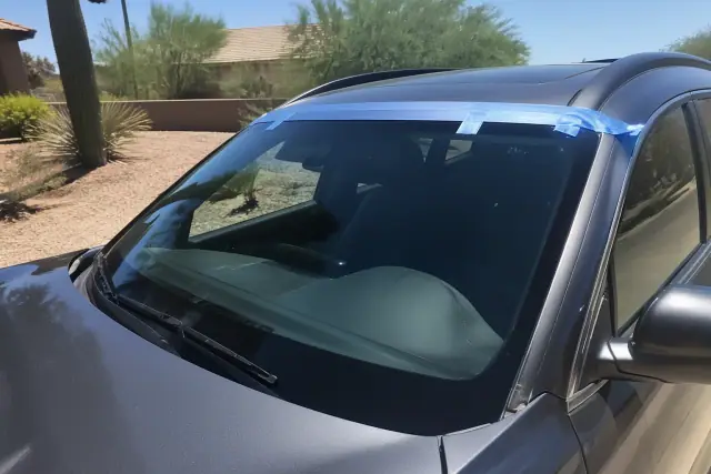 Newly installed car windshield with retention tape on a vehicle parked in Phoenix, AZ.
