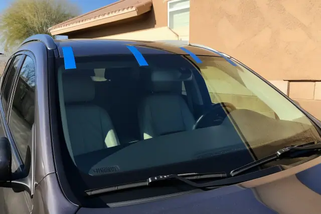 Newly installed car windshield with retention tape on a vehicle exterior in Phoenix, AZ.