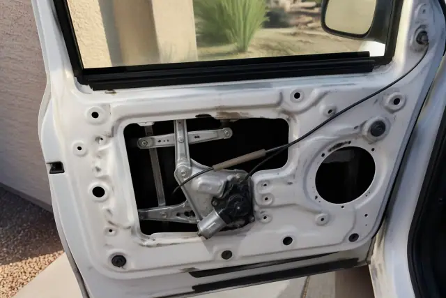 Technician replacing a car window regulator and motor inside a door panel at a jobsite in Phoenix, AZ.