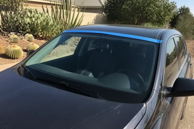 Newly installed car windshield with retention tape in a desert landscape in Chandler, AZ.