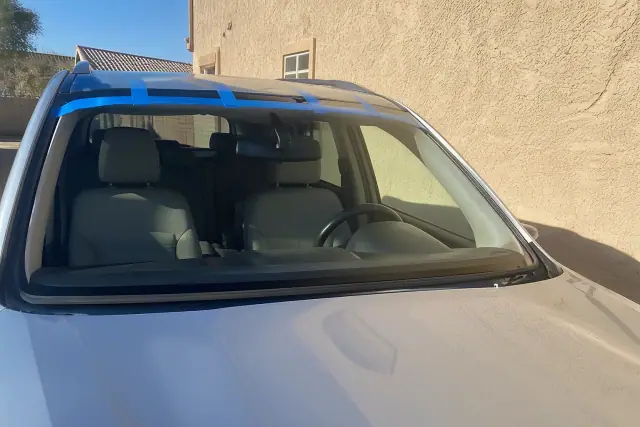 Newly installed windshield with retention tape on a car at a residential site in Phoenix, AZ.