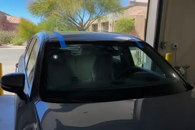 Newly installed windshield with retention tape on a vehicle at a job site in Scottsdale, AZ.