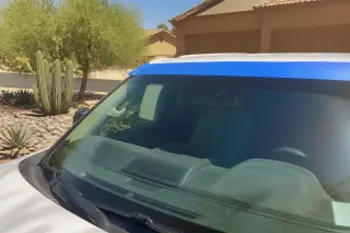 Newly installed car windshield with retention tape parked in a sunny desert driveway in Phoenix, AZ.