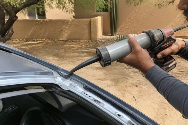 Black urethane adhesive being applied to a vehicle windshield frame at a jobsite in Phoenix, AZ.