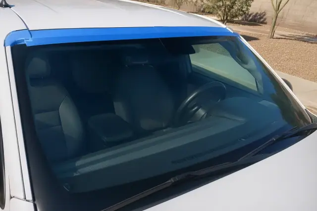 Newly installed windshield on a vehicle parked on a dusty concrete lot in Phoenix, AZ.