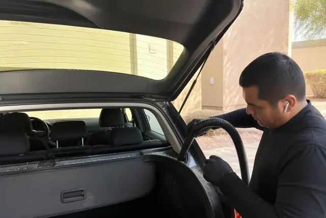 A technician removing broken glass from a vehicle's rear hatch during a glass replacement in Phoenix, AZ.