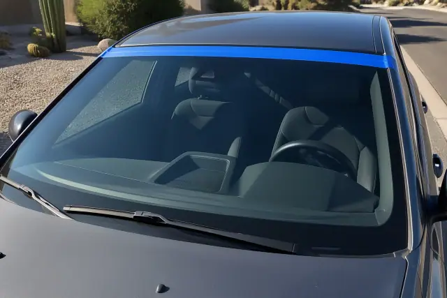 OEM windshield glass installed on a vehicle with retention tape in Phoenix, AZ, set against a desert landscape.
