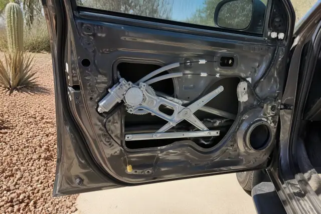 A vehicle door with the interior panel removed to show a window regulator and motor repair in Phoenix, AZ.