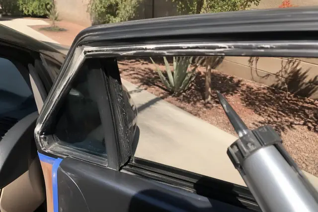 Technician preparing a car window channel with adhesive for glass replacement in Phoenix, AZ.