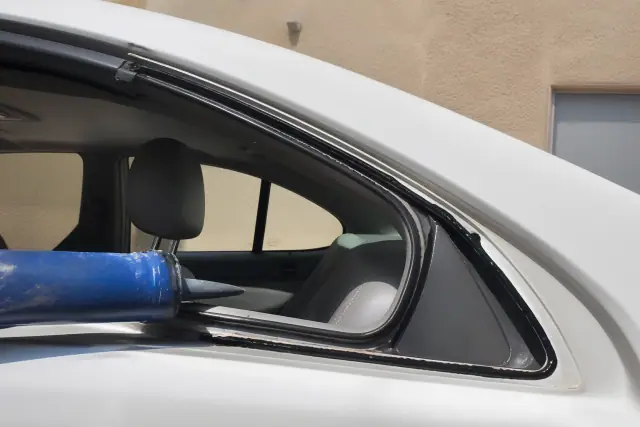 Technician applying adhesive to a car door frame for quarter glass replacement in Phoenix, AZ.