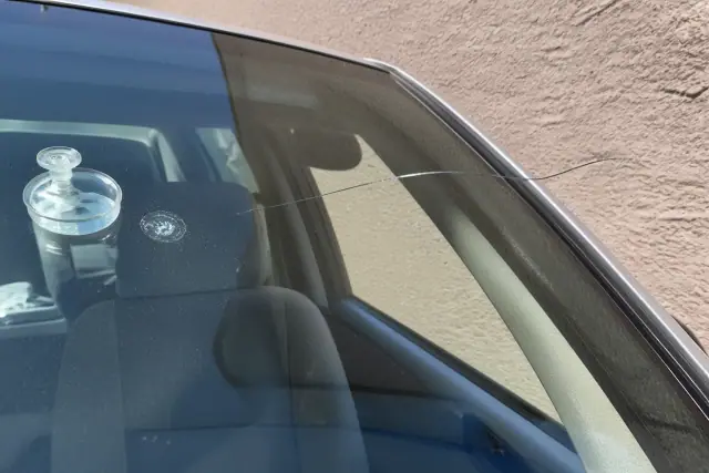 A resin injector tool attached to a windshield star chip next to a six-inch crack on a vehicle in Phoenix, AZ.