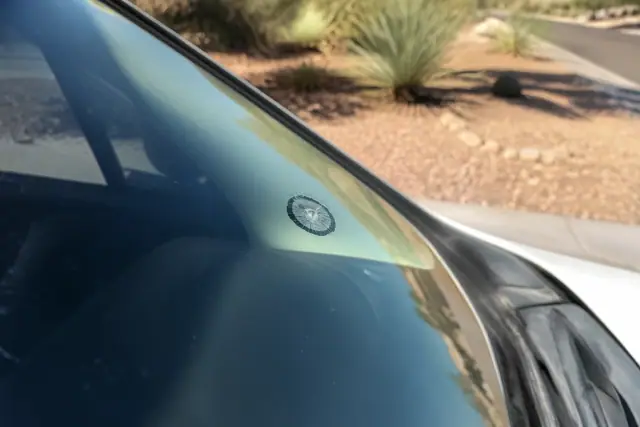 Close-up of a quarter-sized chip in a vehicle windshield at a jobsite in Phoenix, AZ, with desert landscape in the