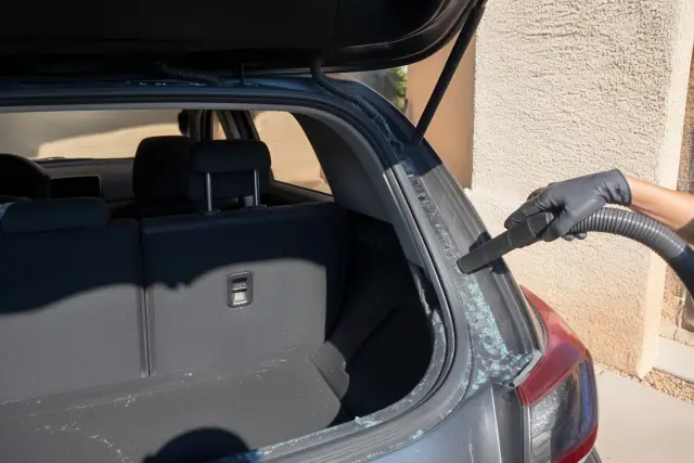 Technician removing broken rear windshield glass from a hatchback in Tempe, AZ.