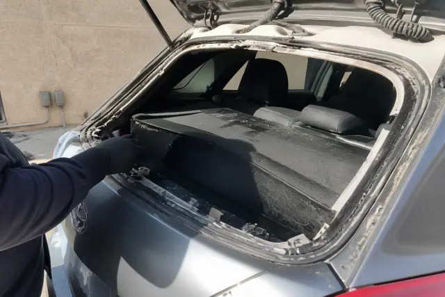 Technician removing broken rear glass from a hatchback vehicle during a windshield replacement in Phoenix, AZ.