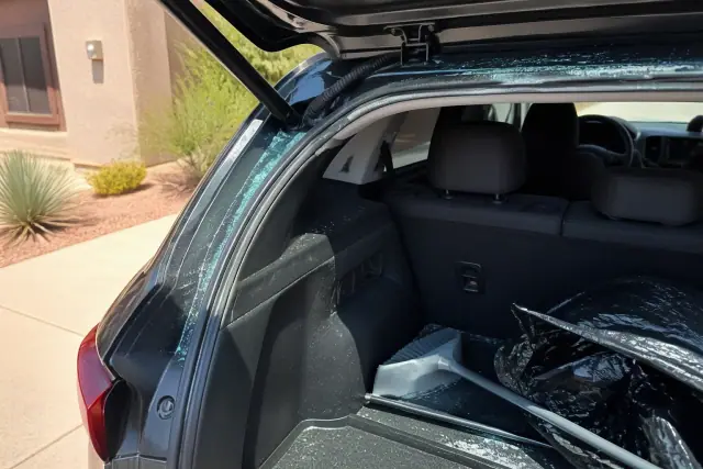 Broken glass fragments being removed from a hatchback trunk at a job site in Gilbert, AZ.