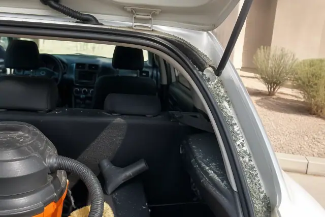 Technician removing broken glass from a car hatchback during a rear windshield replacement in Chandler, AZ.