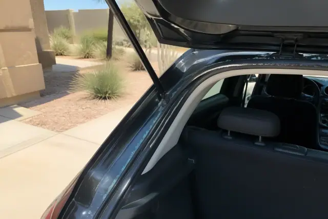 Broken glass fragments being removed from the hatchback trunk weather stripping during an auto repair in Phoenix, AZ.