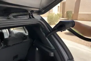 Technician using a vacuum to clean glass fragments from a hatchback trunk in Phoenix, AZ.