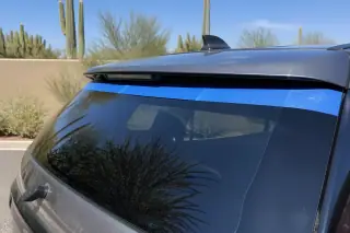 Newly installed car rear glass with professional retention tape in a sunny Phoenix, AZ landscape.