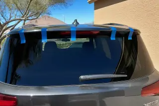 Newly installed rear car glass with retention tape parked by a stucco wall in Phoenix, AZ.
