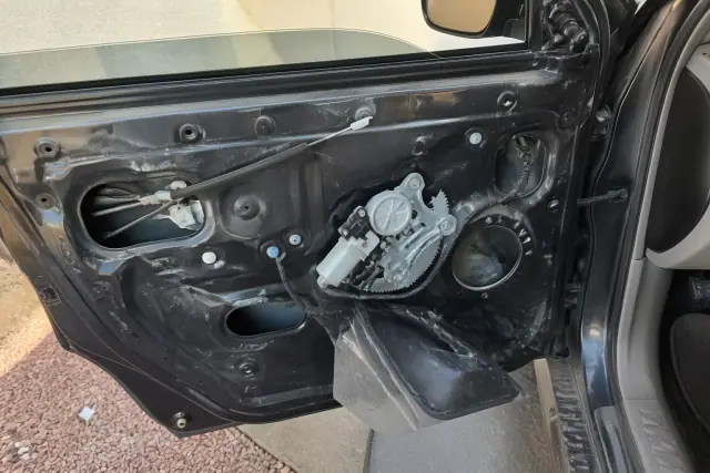 Window regulator assembly and electric motor inside a vehicle door in Phoenix, AZ.