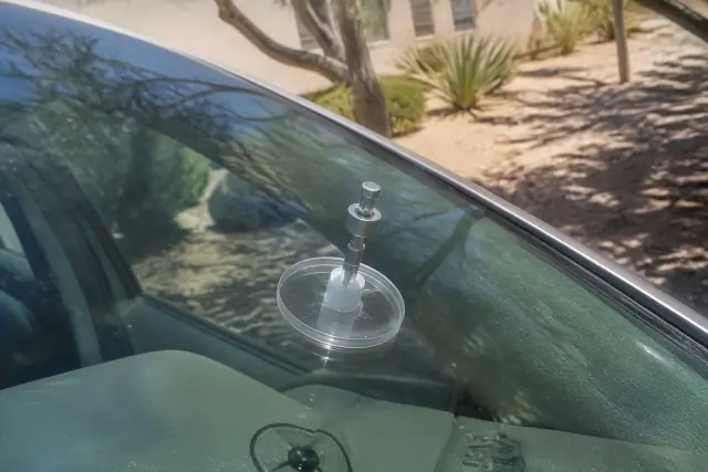 Close-up of a resin injector tool repairing a star break on a car windshield in Phoenix, AZ.