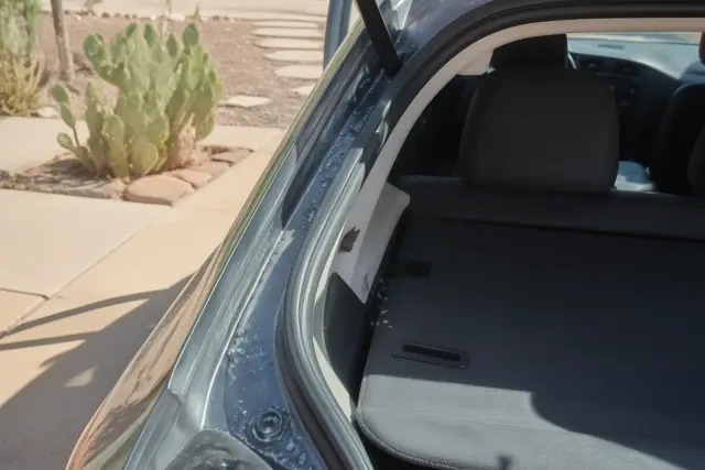 Broken glass fragments being removed from a hatchback trunk weather stripping at a job site in Phoenix, AZ.