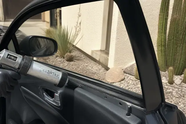 Technician applying adhesive to a car window channel during an auto glass repair in Phoenix, AZ.