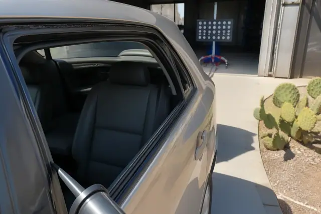 Technician applying adhesive to a car door frame for side window replacement in Tempe, AZ.