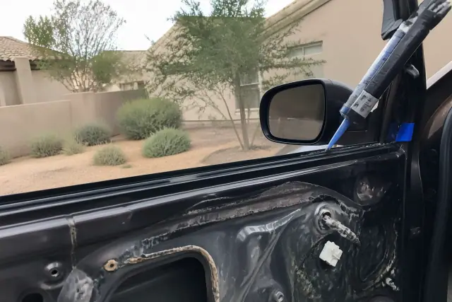 Technician applying adhesive to a door frame during a side window replacement in Paradise Valley, AZ.