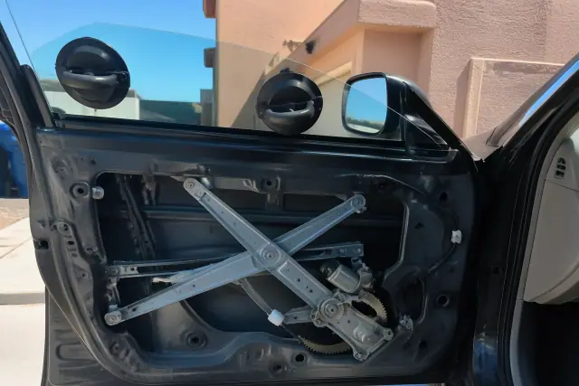Technician installing a new car side window in a residential driveway in Phoenix, AZ.