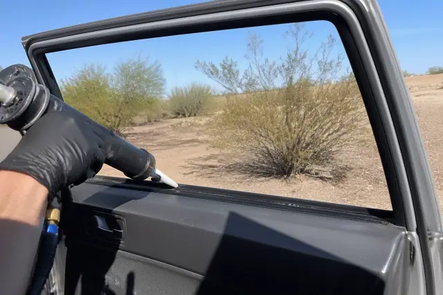 Technician prepping a car door window channel for side glass replacement in Mesa, AZ.