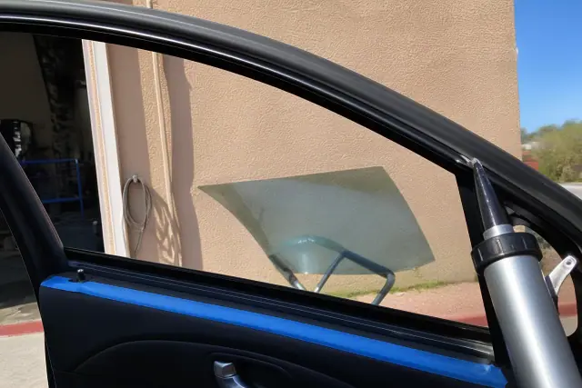 A technician preparing a car door frame for side window replacement at an auto shop in Chandler, AZ.