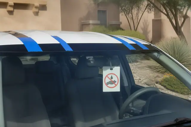 Instructional tag hanging from a car mirror with retention tape on a new windshield at a home in Phoenix, AZ.