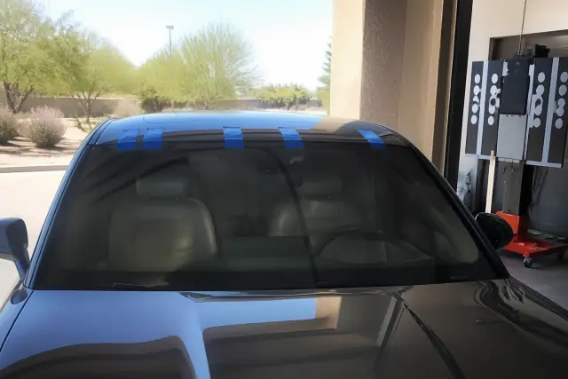 Newly installed windshield with retention tape in a Phoenix, AZ service bay with a digital calibration target.