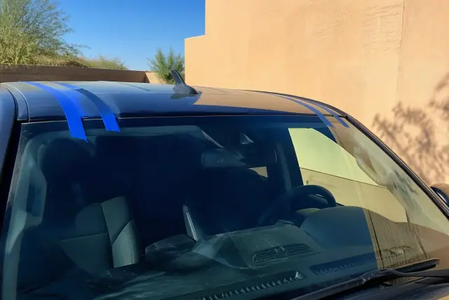 Newly installed car windshield with retention tape on a vehicle exterior in Phoenix, AZ.