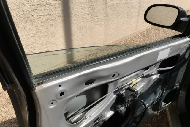 Stress crack in a vehicle window glass near the door frame in Phoenix, AZ, with the interior panel removed.