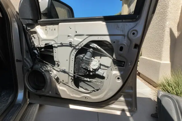 Open vehicle door panel showing the window regulator and motor being repaired at a home in Phoenix, AZ.