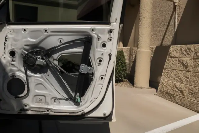 An exposed vehicle door interior with the window regulator and motor visible during repair work in Phoenix, AZ.