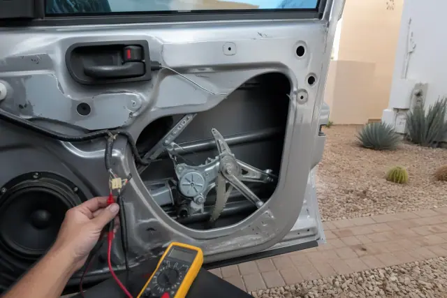Technician performing a window regulator diagnosis on a car door in Phoenix, AZ.